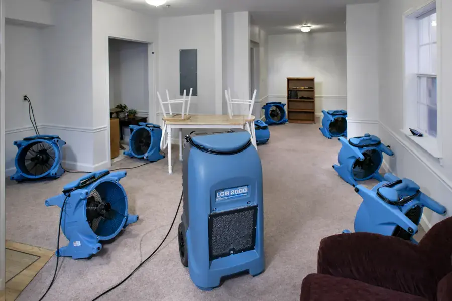 Air movers and an LGR dehumidifier drying a living room after water damage in O'Fallon, MO